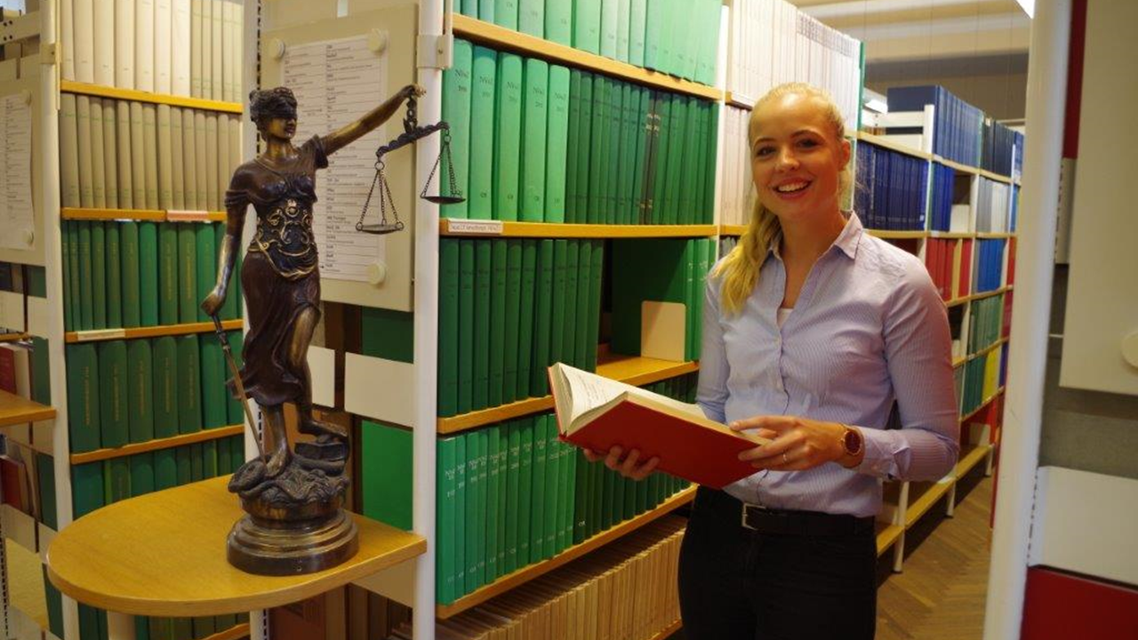 Eine Mitarbeiterin der Justiz steht vor Bücherregalen in der Bibliothek des Brandenburgischen Oberlandesgerichts.